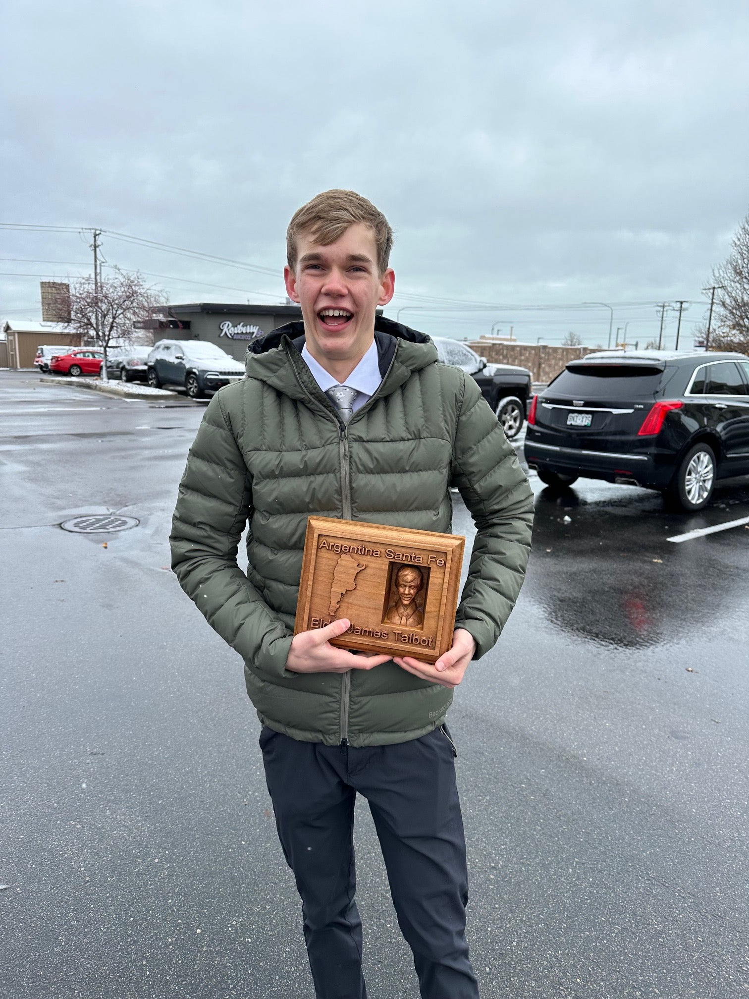 New Missionary holding a wooden plaque outdoors in a parking lot