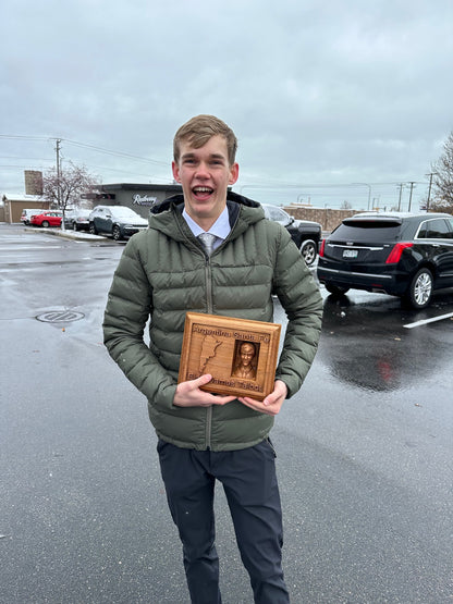 New Missionary holding a wooden plaque outdoors in a parking lot